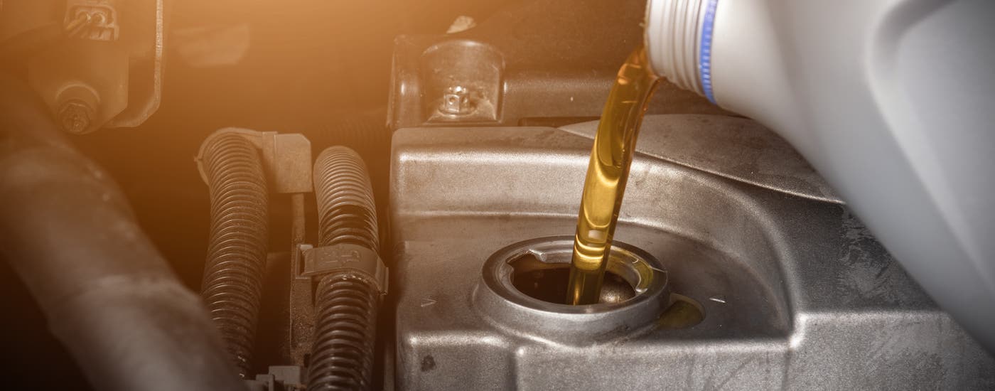 Oil is bing poured from a gray bottle into an engine at a Chevy dealer in MS.