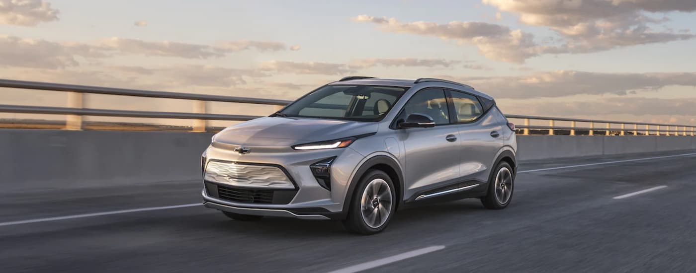 A new Chevy SUV, a silver 2022 Chevy Bolt EUV, is driving on a highway.