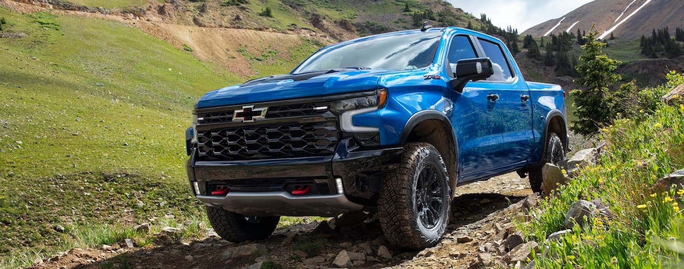 A blue 2022 Chevy Silverado 1500 ZR2 is shown on a dirt path after visiting a Farmington GM dealer.