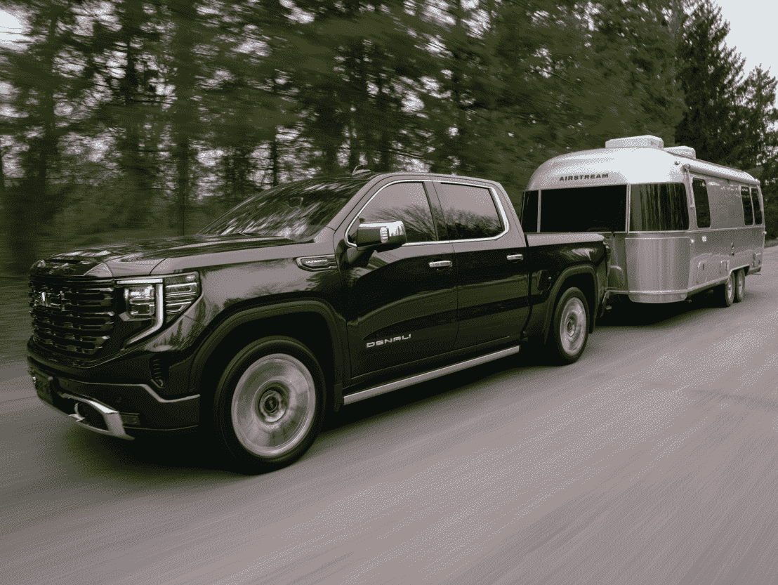A GMC Sierra 1500 tows a trailer behind it.