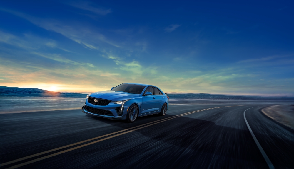 Blue 2025 Cadillac CT4-V Series driving on road with setting sun and blue skies