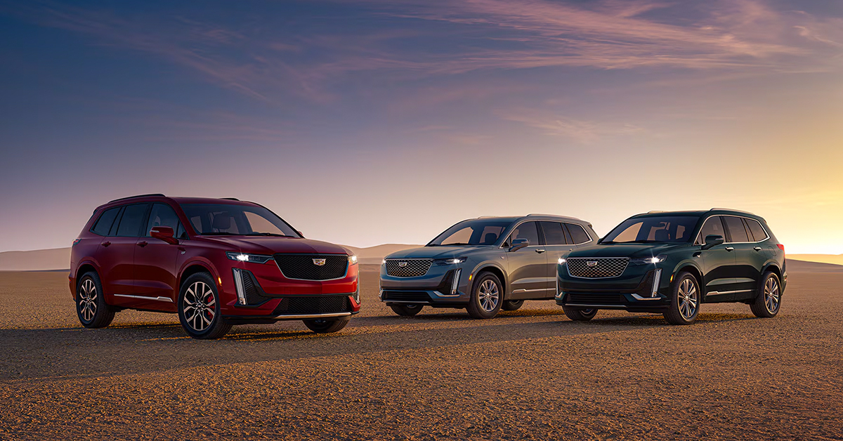 Three Cadillac SUVs parked in the desert at sunset