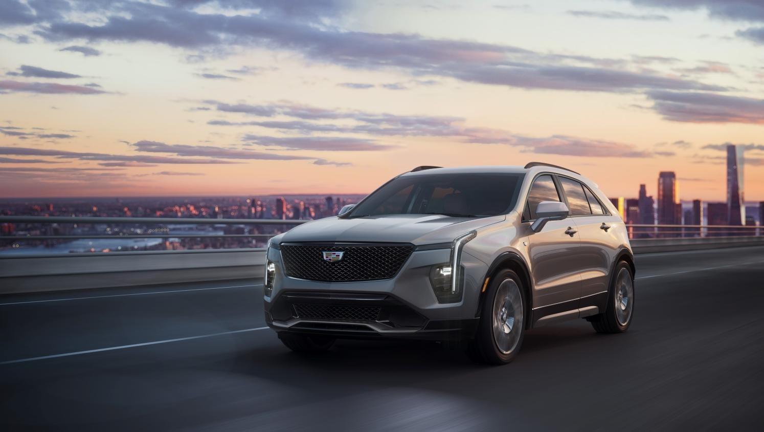 Silver 2025 Cadillac XT5 with city skyline in background