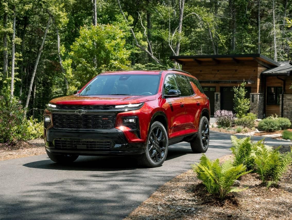 Red 2024 Chevy Traverse in driveway of home in the woods