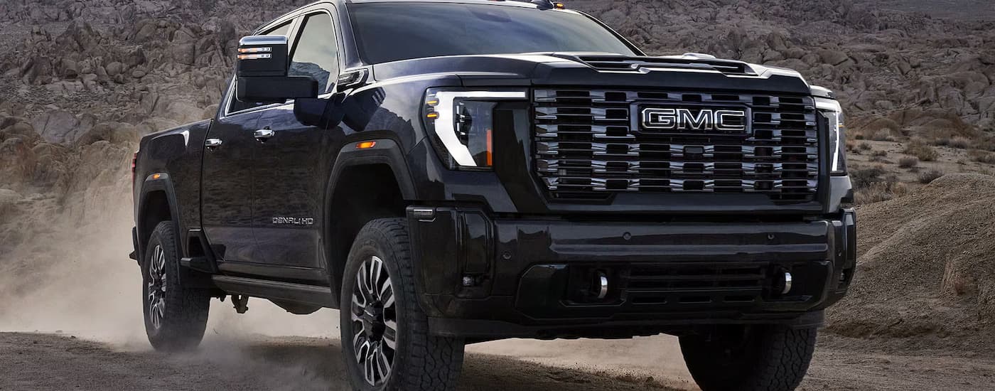 A black 2025 GMC Sierra 2500 HD Denali for sale on a dusty dirt road.