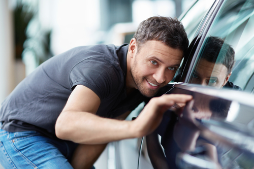 man admiring a new car in the showroom