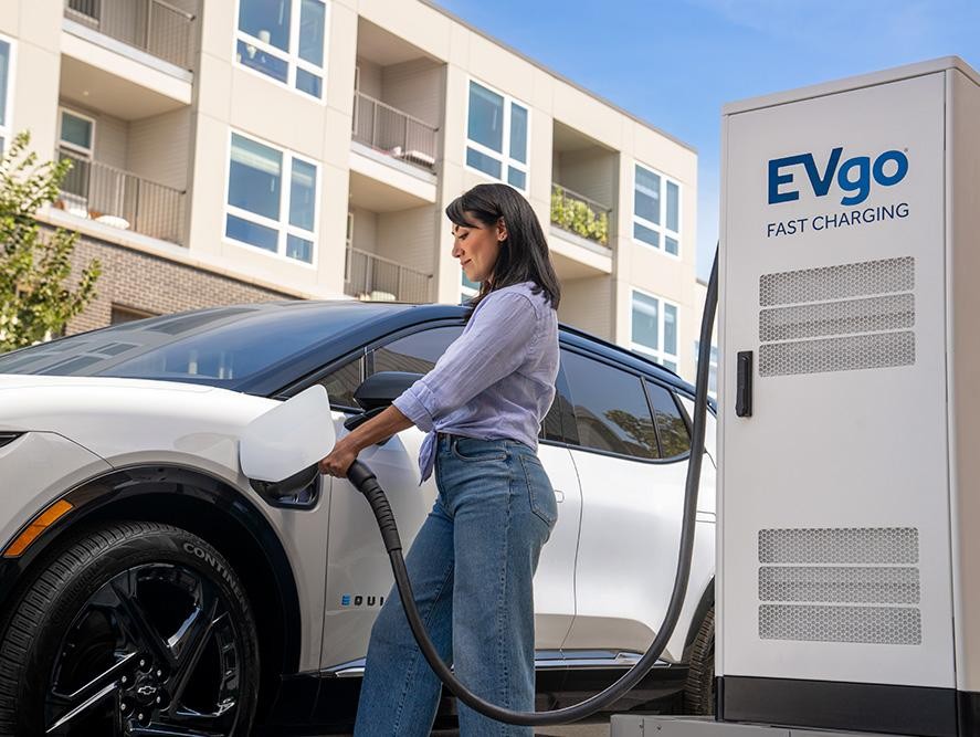 Woman charging her Chevy Equinox EV at an EVgo Fast Charging Station
