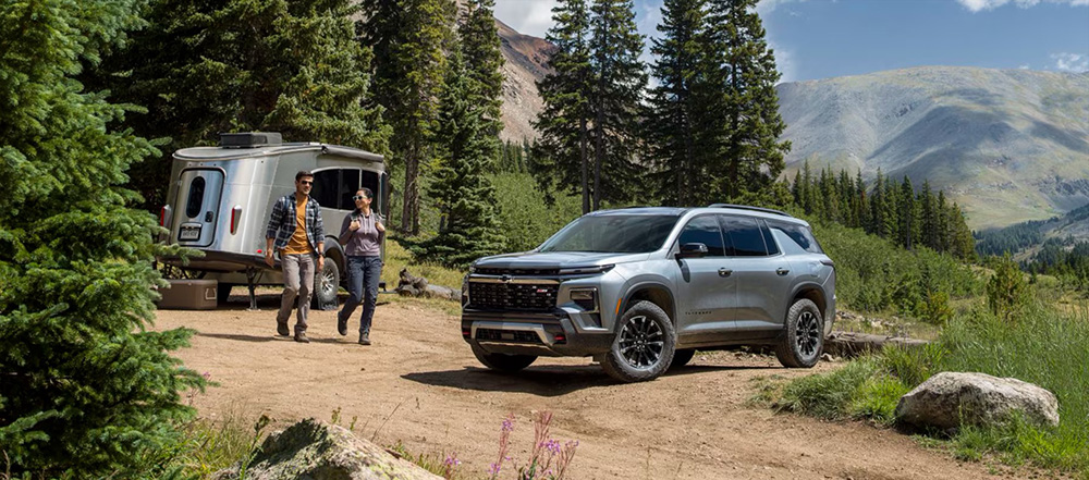 2025 Chevy Traverse next to a camper and couple hiking