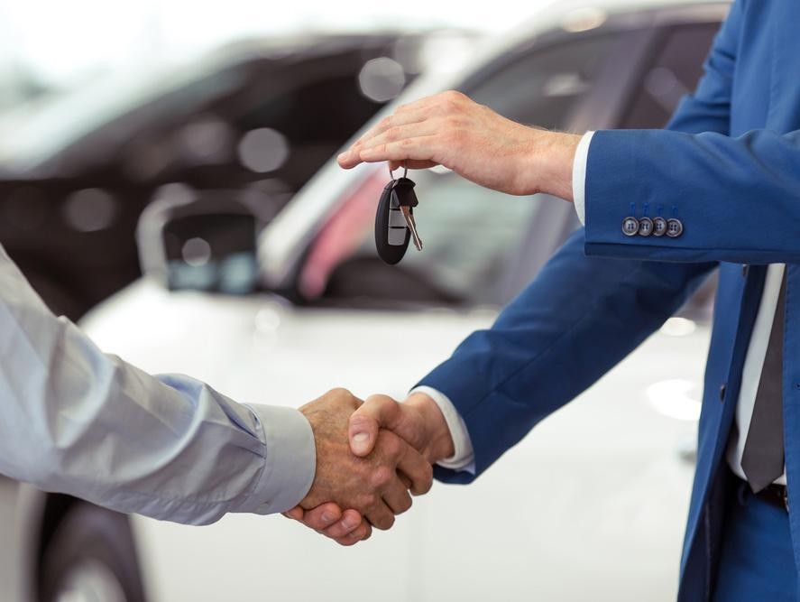 Car salesman handing keys over to new car owner
