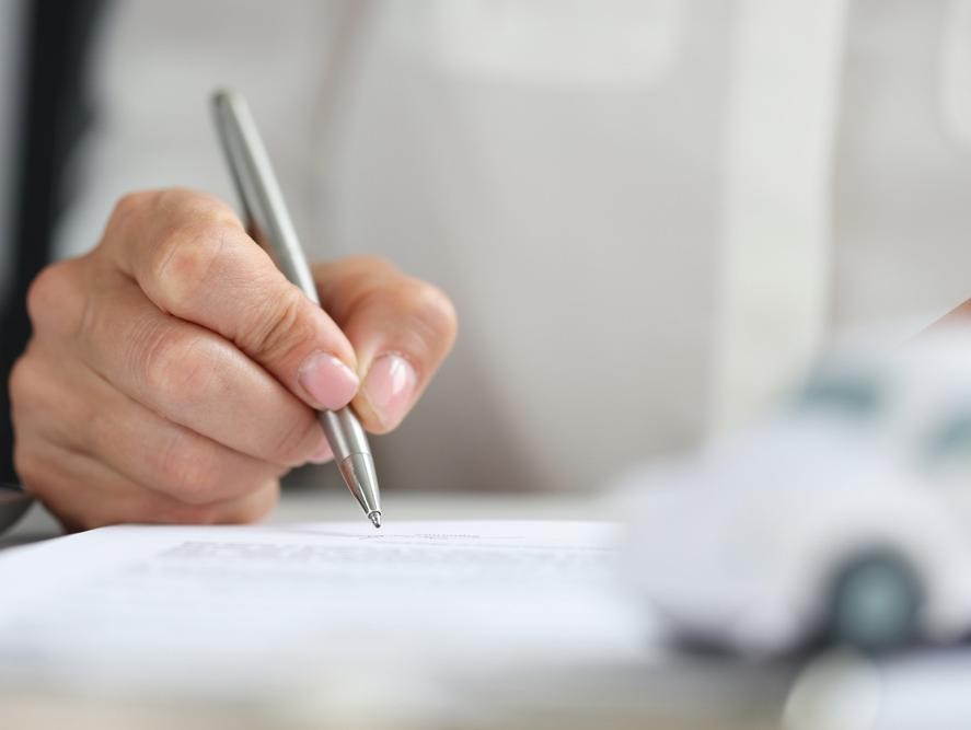 Man signing car paperwork after purchasing a vehicle