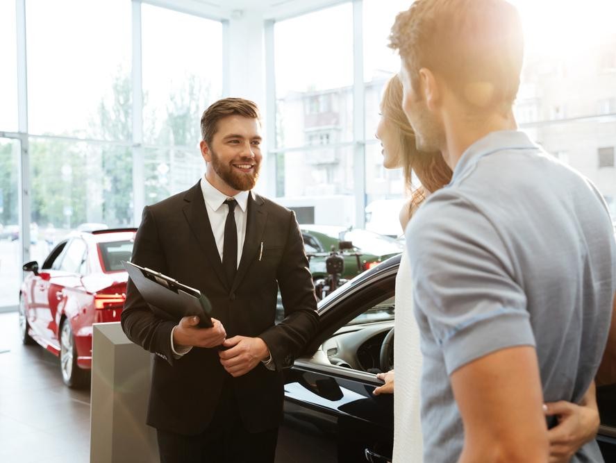 Car salesman talking to potential buyers in a vehicle showroom