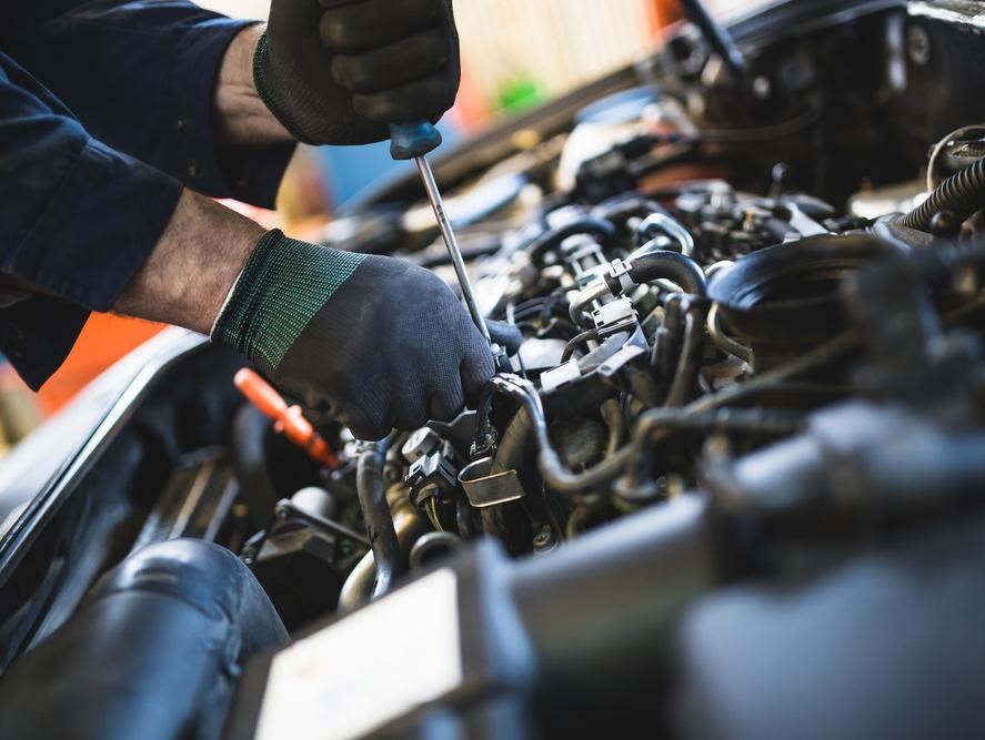 Service technician using tools on a car engine