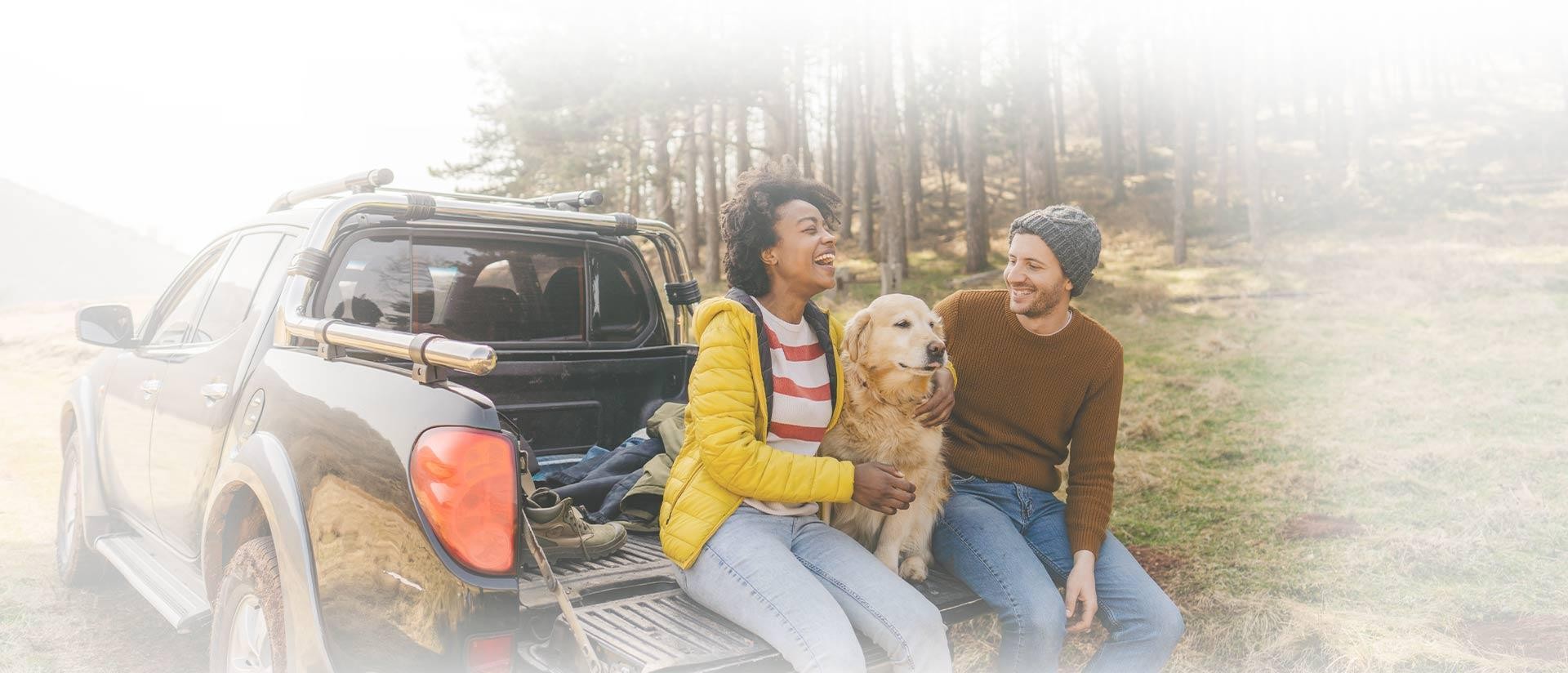 Couple with a dog in the back of a truck