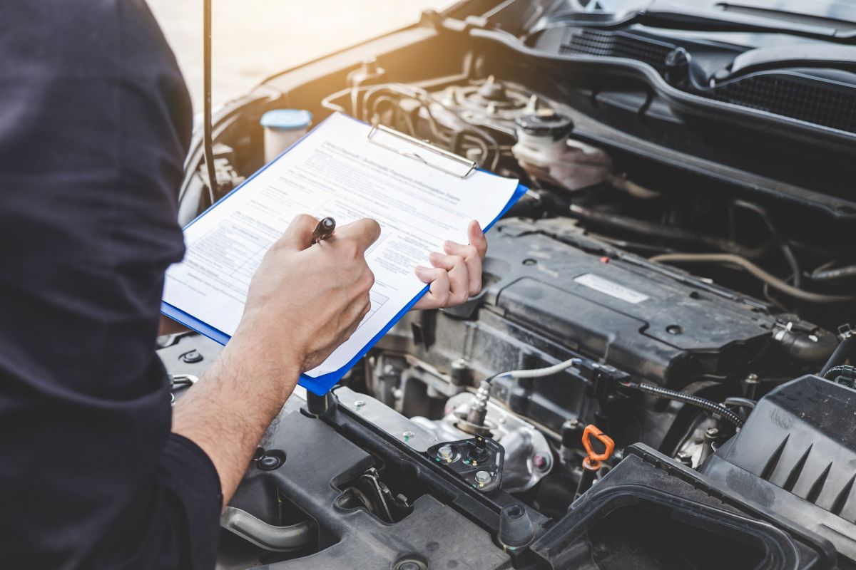 Technician servicing a vehicle, checking things off on a clipboard