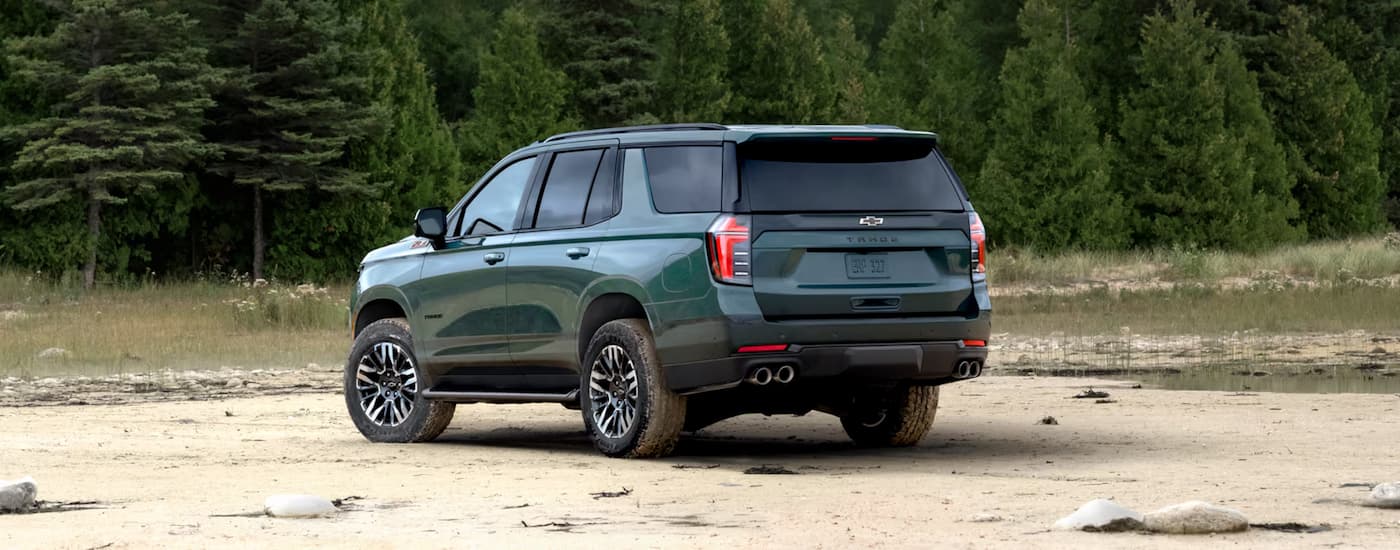 A rear view of a green 2025 Chevy Tahoe Z71 for sale parked on sand.