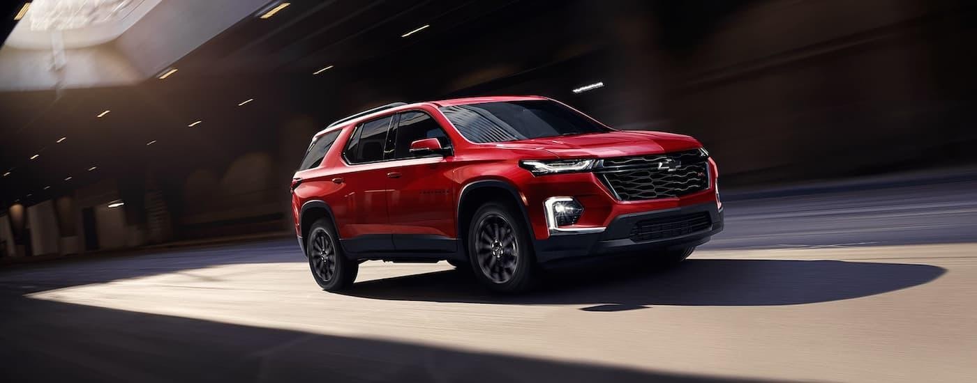 A red 2023 Chevy Traverse RS for sale is shown driving through a tunnel.
