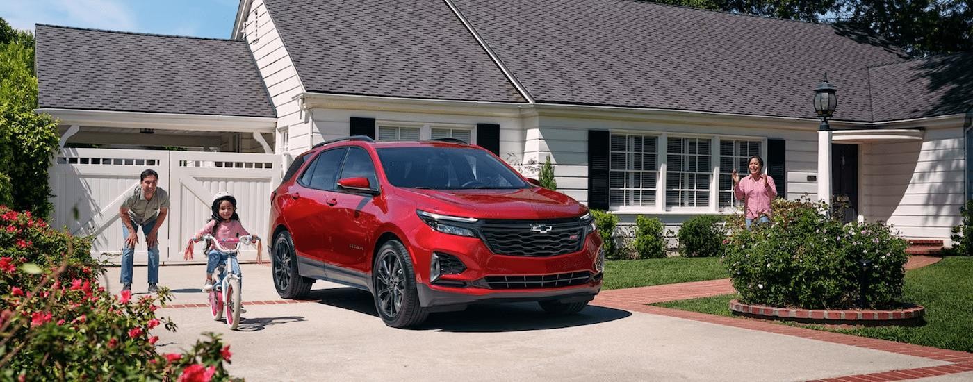 A red 2024 Chevy Equinox RS for sale is shown parked in a driveway. 