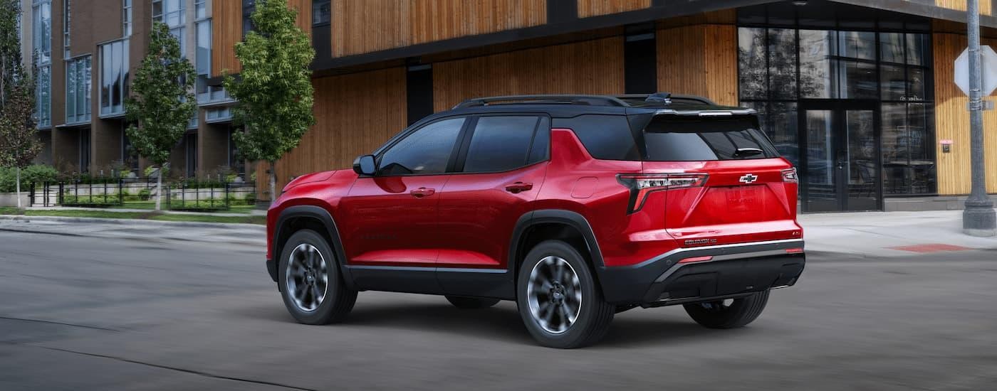 A red 2025 Chevy Equinox RS for sale near Leesville driving on a city street.