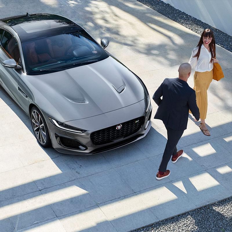 Happy couple with Jaguar car parked