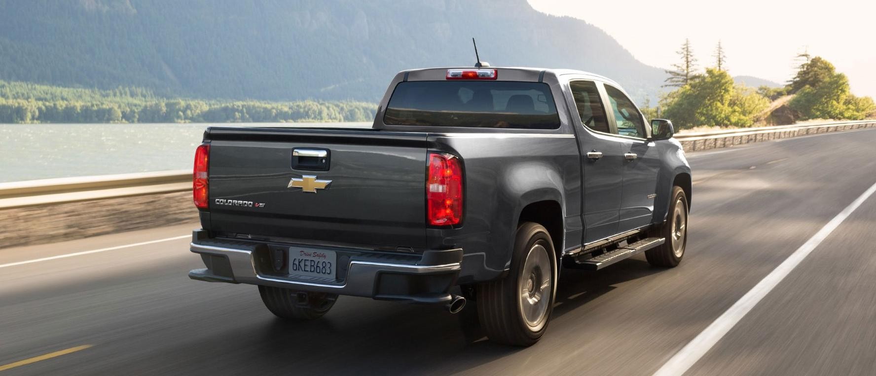 Black 2019 Chevy Colorado driving on a road near lake.