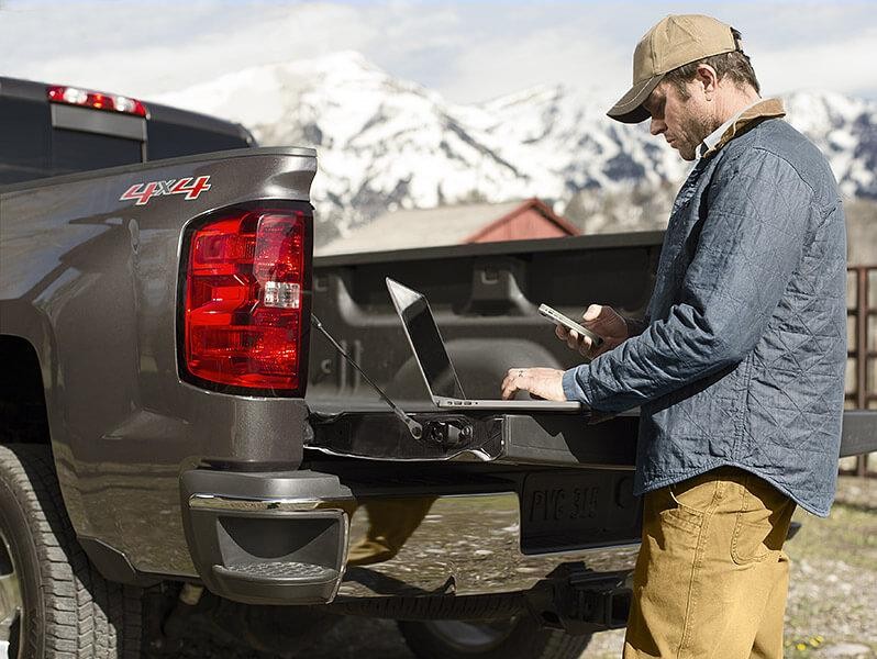 Man working on laptop on tailgate Man working on laptop on tailgate