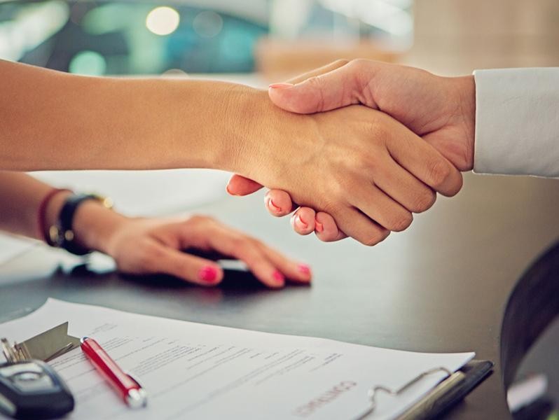 Woman and man shaking hands over contract.