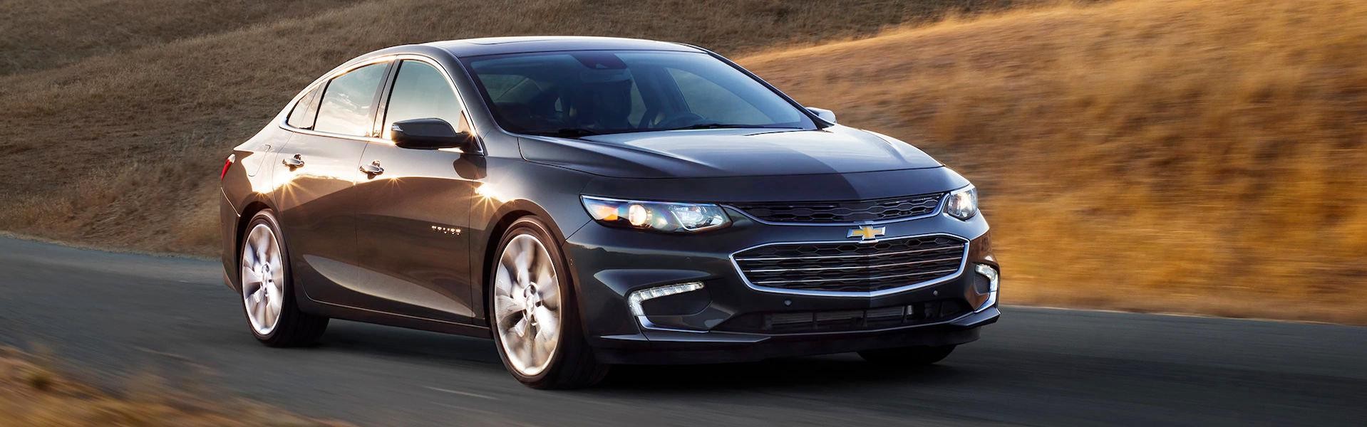2018 Chevy Malibu driving along a grassy road.