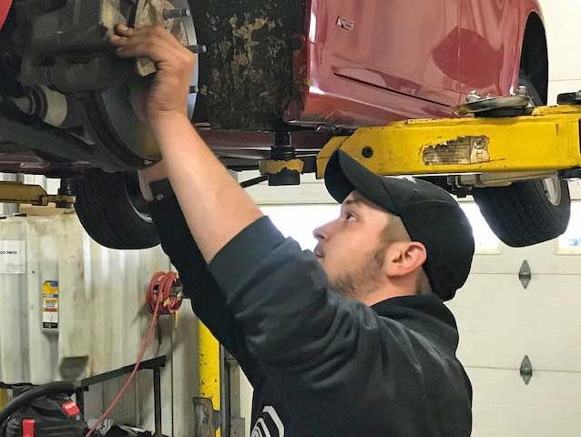 Service technician working under the hood of a car.