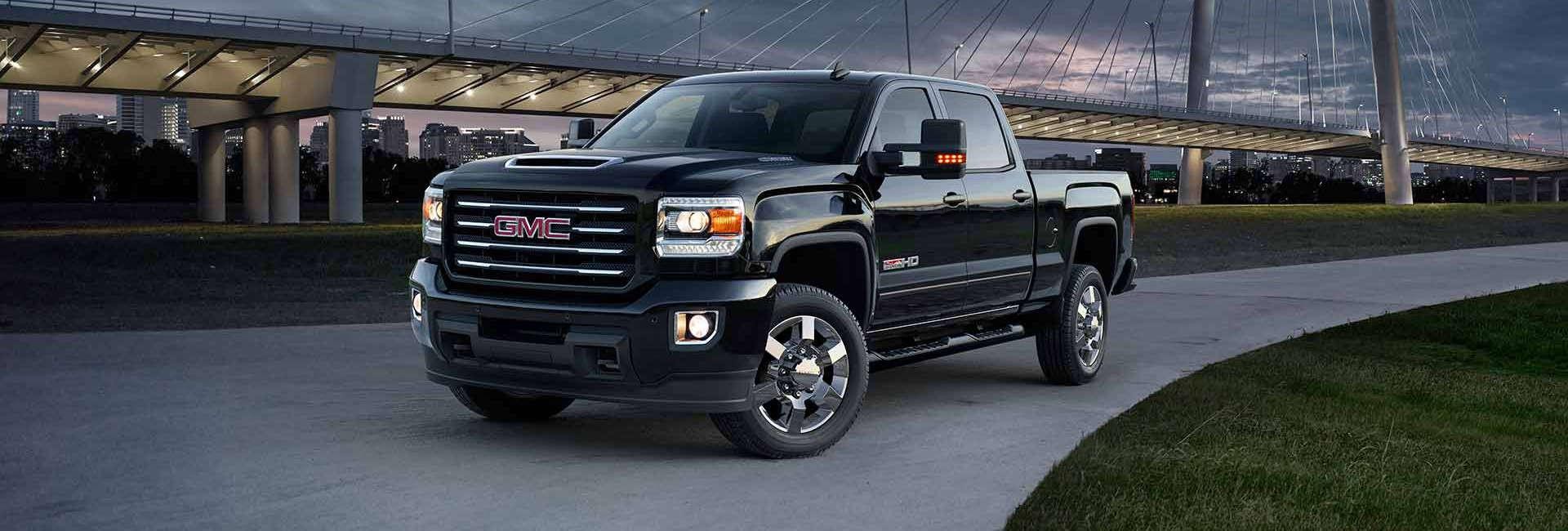 A black 2018 GMC Sierra 2500HD parked in a driveway at dusk