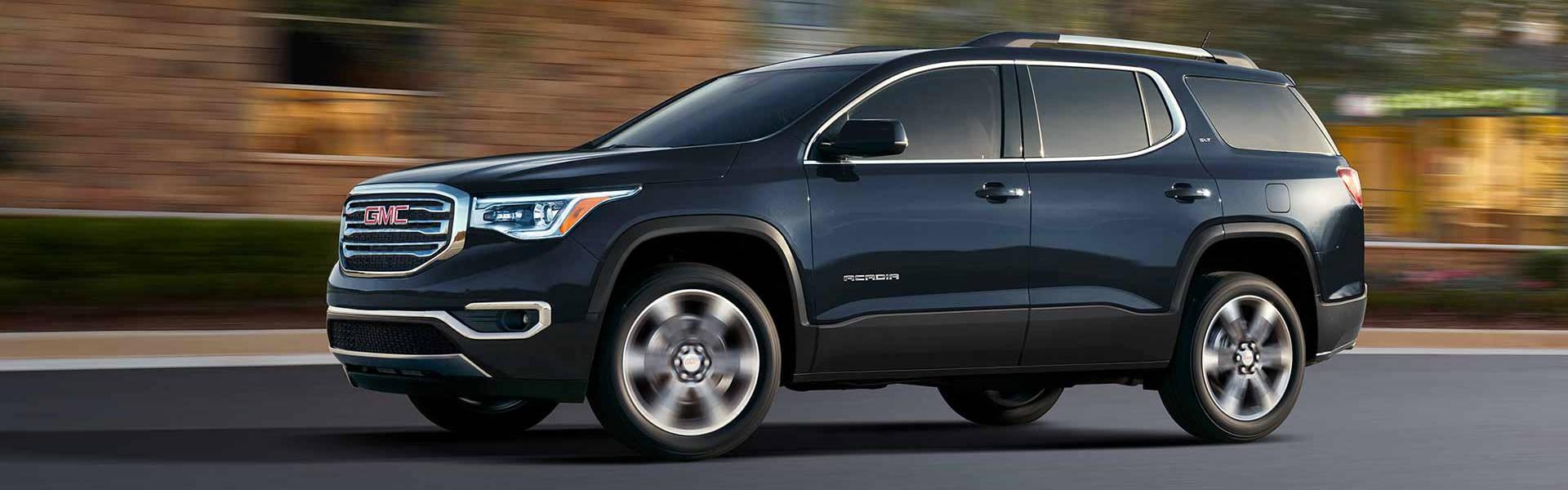 The 2018 GMC Acadia driving down a road fast. 