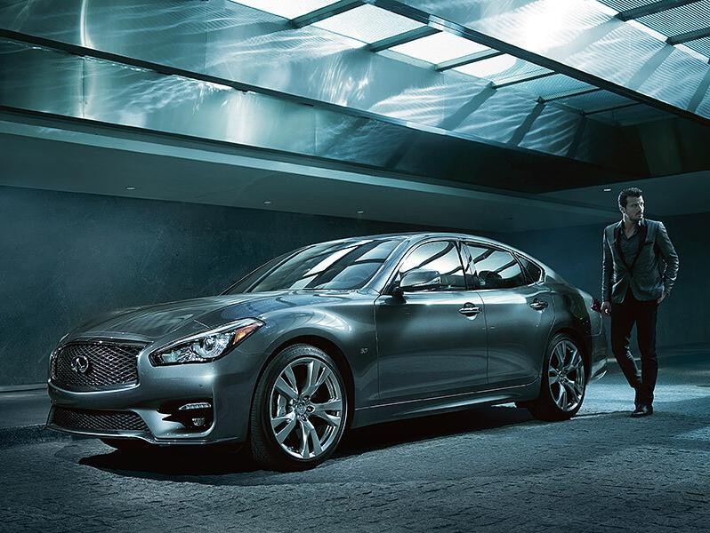 Man walking towards an Infiniti QX70 parked in a modern garage.