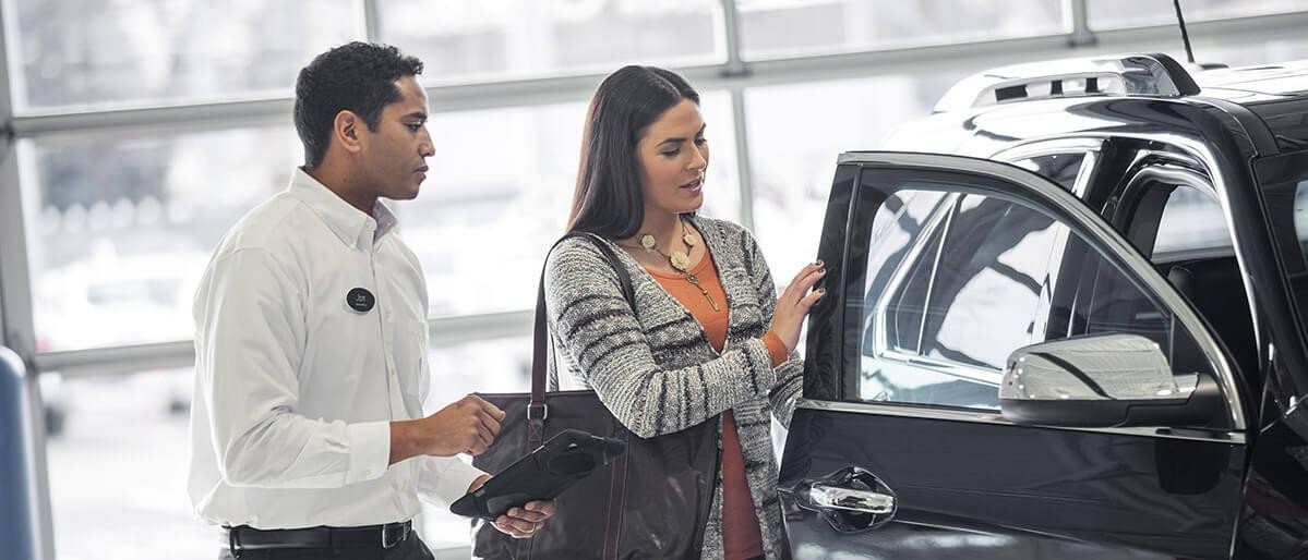 Car salesman showing a woman a new vehicle.