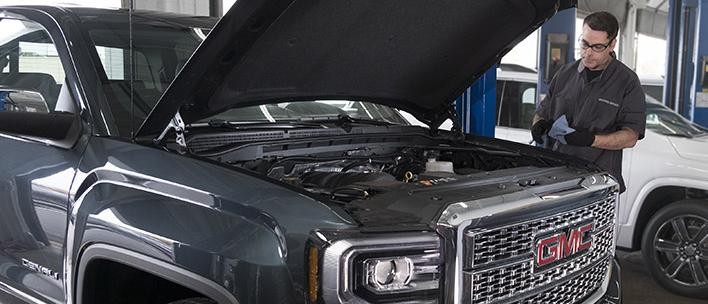 Service technician inspecting a GMC Sierra 1500 Denali.
