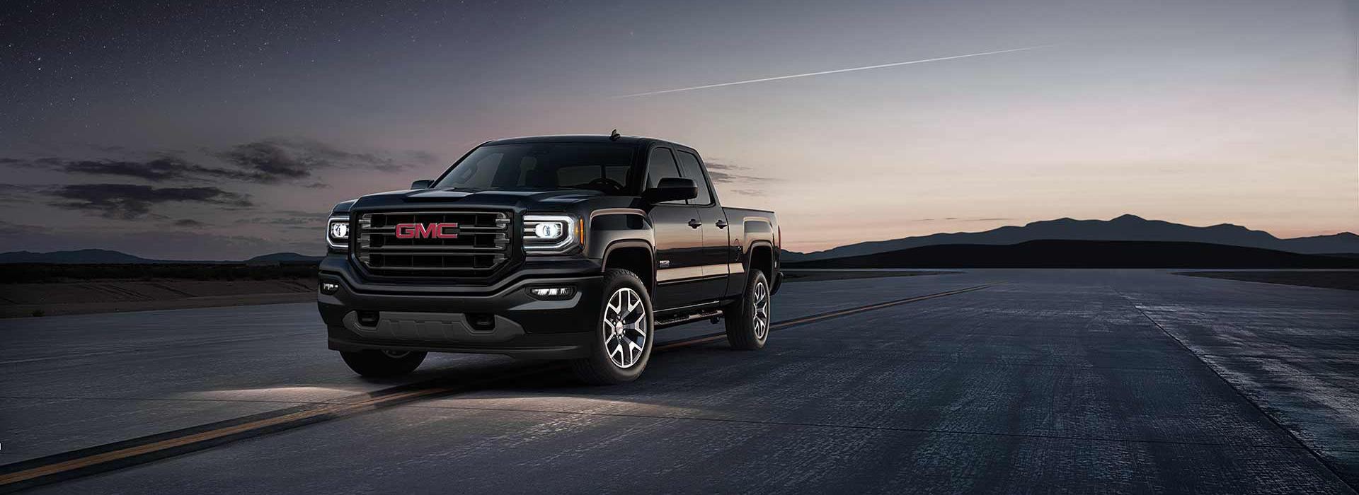 A black 2018 GMC Sierra sitting parked at night on a runway