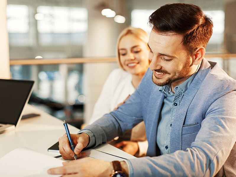 Young business couple signing a contract.