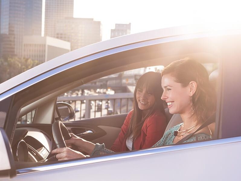 Two women driving and smiling in their car.