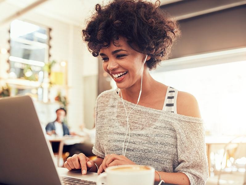 Happy woman at cafe using laptop