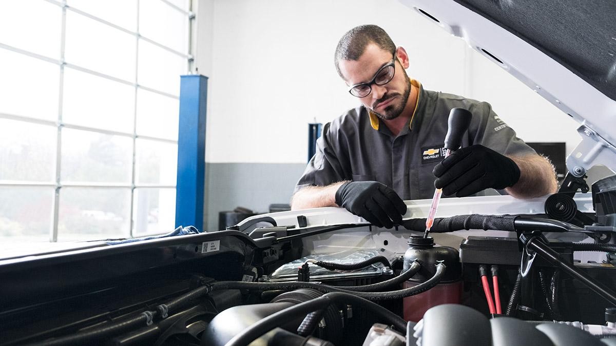 Service technician working under the hood of a car.