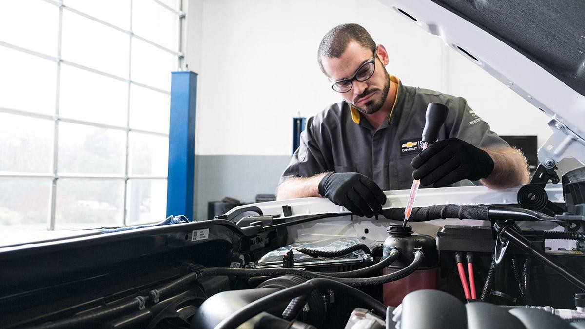 Service technician working under the hood of a car. Service technician working under the hood of a car.