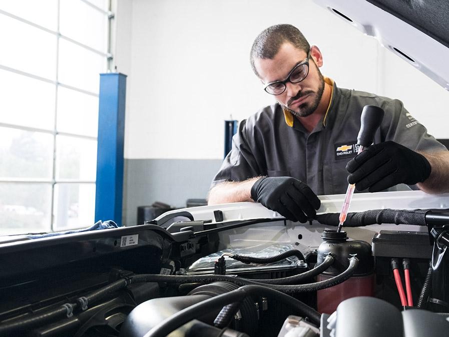 Service technician working under the hood of a car.