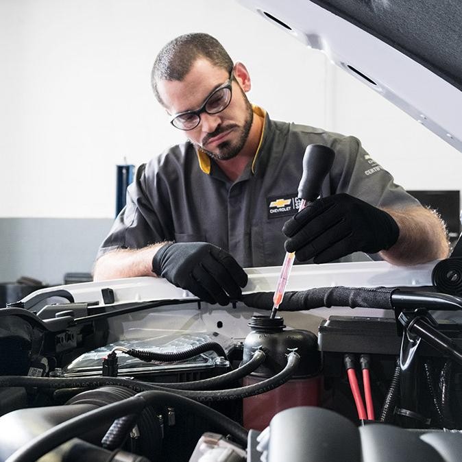 Service technician working under the hood of a car.